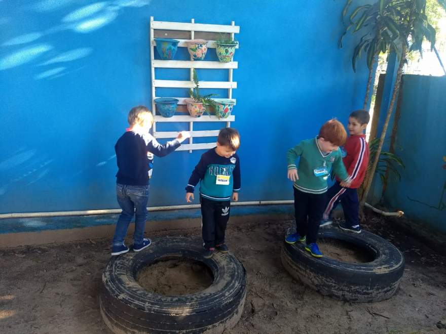 Crianças brincando com pneus, uma das ações do projeto