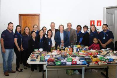 Autoridades do município e servidores com o palestrante junto aos alimentos arrecadados para programas assistenciais